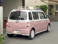 a pink minivan parked in front of a house on the side of the road