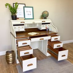 a white desk with drawers and a potted plant