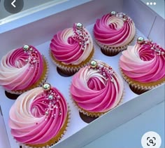 four cupcakes with pink frosting in a box