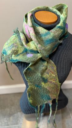 a green and blue scarf sitting on top of a mannequin's head