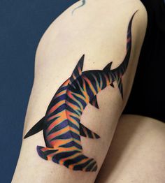 a colorful fish tattoo on the right thigh