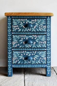 a blue and white painted dresser sitting on top of a wooden floor next to a wall