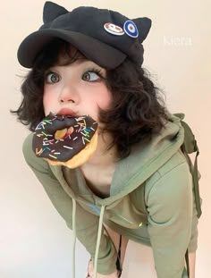 a young woman wearing a cat hat and eating a donut with chocolate sprinkles