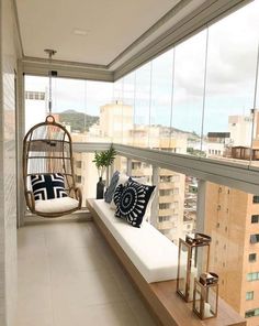 a balcony with a swing chair and pillows on the floor next to a large window