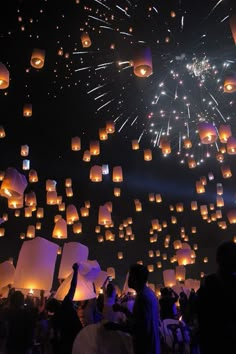 people are flying lanterns in the air at night