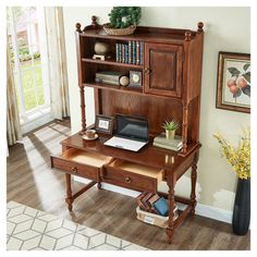 a wooden desk with a computer on it and bookshelf in front of the window