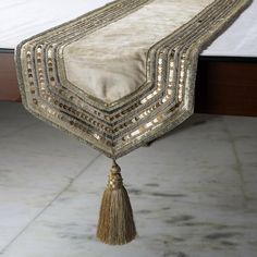 a table runner with tassels and beads hanging from it's sides on a marble floor