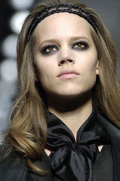 a woman with long hair wearing a black shirt and bow tie on the catwalk