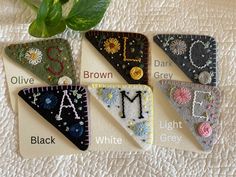 four pieces of felt with embroidered letters and flowers on them, all in different colors