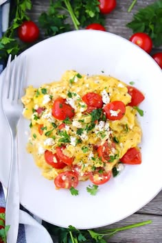 a white plate topped with pasta covered in cheese and tomatoes next to some parsley