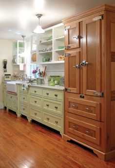 a large kitchen with wooden floors and green cupboards on either side of the sink