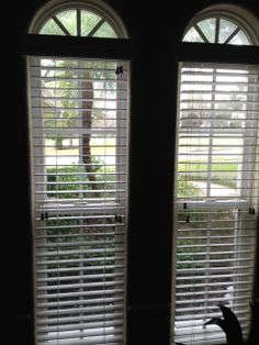 two windows with blinds open in a dark room, one is looking out the window