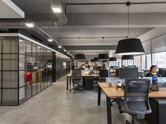 an office with people working at their desks in the middle of the room and lots of windows