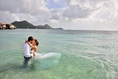 a bride and groom kissing in the water on their wedding day at an island resort