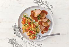 a white plate topped with meat and veggies on top of a wooden table