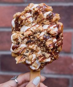 a person holding up an ice cream sundae with chocolate and marshmallows