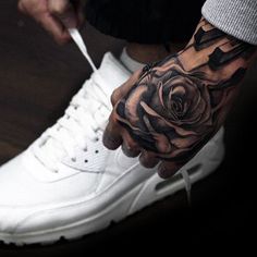 a man with a rose tattoo on his left hand is holding a pair of scissors