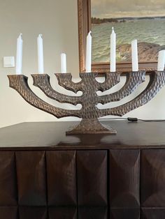 a large menorah with white candles on it's stand in front of a painting