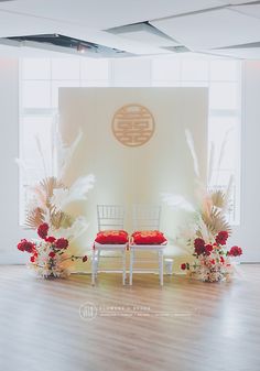 two white chairs sitting on top of a hard wood floor next to flowers and plants