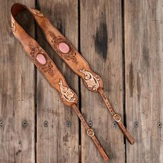 two wooden utensils with carved designs on them sitting next to each other in front of wood planks