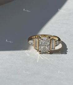 a diamond ring sitting on top of a white table next to a shadow from the floor