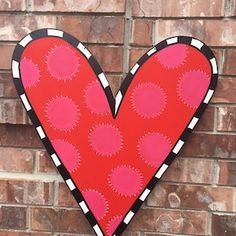 a red heart shaped paper cut out on a brick wall