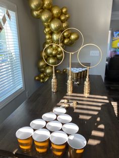 there are many cups on the table with gold balloons in the backgroung