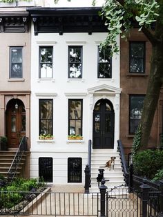 two story brownstone home with black wrought iron fence