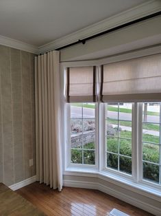 an empty room with three windows and two blinds on the window sill, in front of a wooden floor