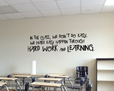 an empty classroom with desks and chairs in front of a wall that says, the class we don't do easy we make every happen through hard work and learning