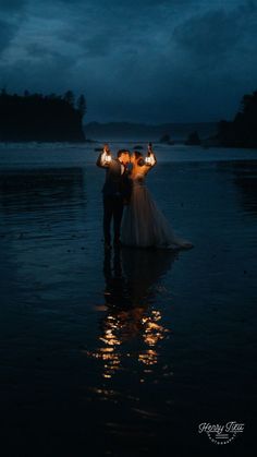 two people standing in the water holding candles