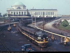 an old train is on the tracks in front of a large building with a domed roof