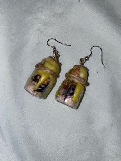 the earrings are made out of glass and decorated with yellow, white and black items