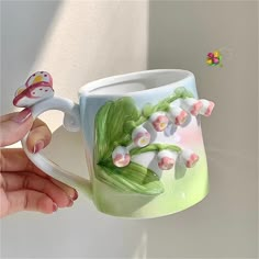 a hand holding a coffee mug with flowers painted on it