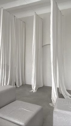 a white room with drapes hanging from the ceiling and two couches on the floor