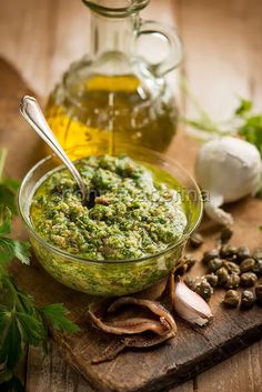 a glass bowl filled with pesto next to garlic and herbs