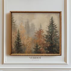 a painting hanging on the wall in front of a white frame with trees painted on it