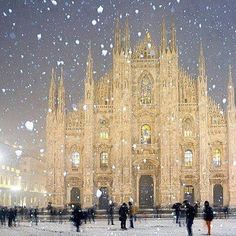 a painting of a cathedral with snow falling on the ground and people standing in front