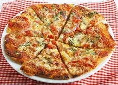 a pizza cut into eight slices on a plate with a red and white checkered tablecloth