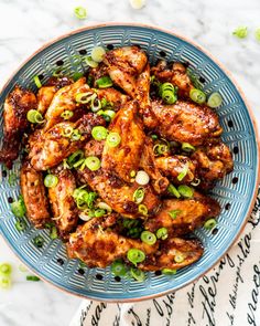 a blue bowl filled with chicken wings and green onions