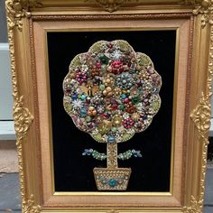 an ornate gold frame with a tree made out of beads and other items on it