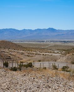 an open field with mountains in the distance and dirt on the ground near by,