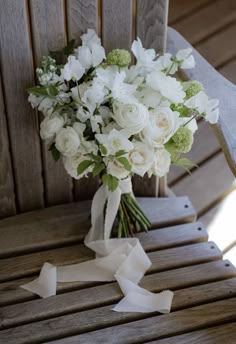 a bouquet of white flowers sitting on top of a wooden chair