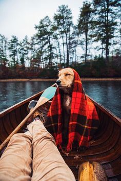 a person is sitting in a boat with a plaid blanket on their head and feet