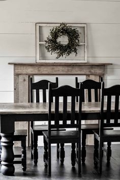 a dining room table and chairs with a wreath on the wall above it in front of a fireplace