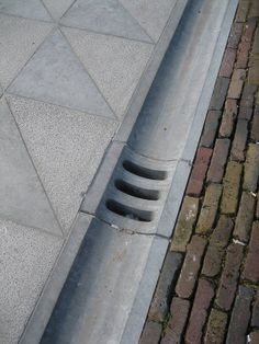 a street drain on the side of a road next to a brick sidewalk with a fire hydrant in it