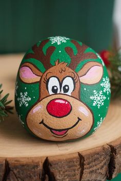 a painted rock with a reindeer's face on it sitting on a tree stump