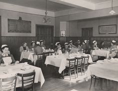 an old black and white photo of women in nurses'hats sitting at tables eating