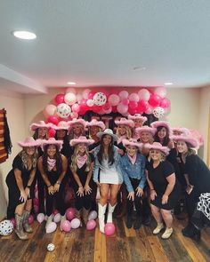 a group of women standing next to each other in front of pink and white balloons