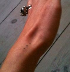 a person's arm with a ring on it and a wooden floor in the background